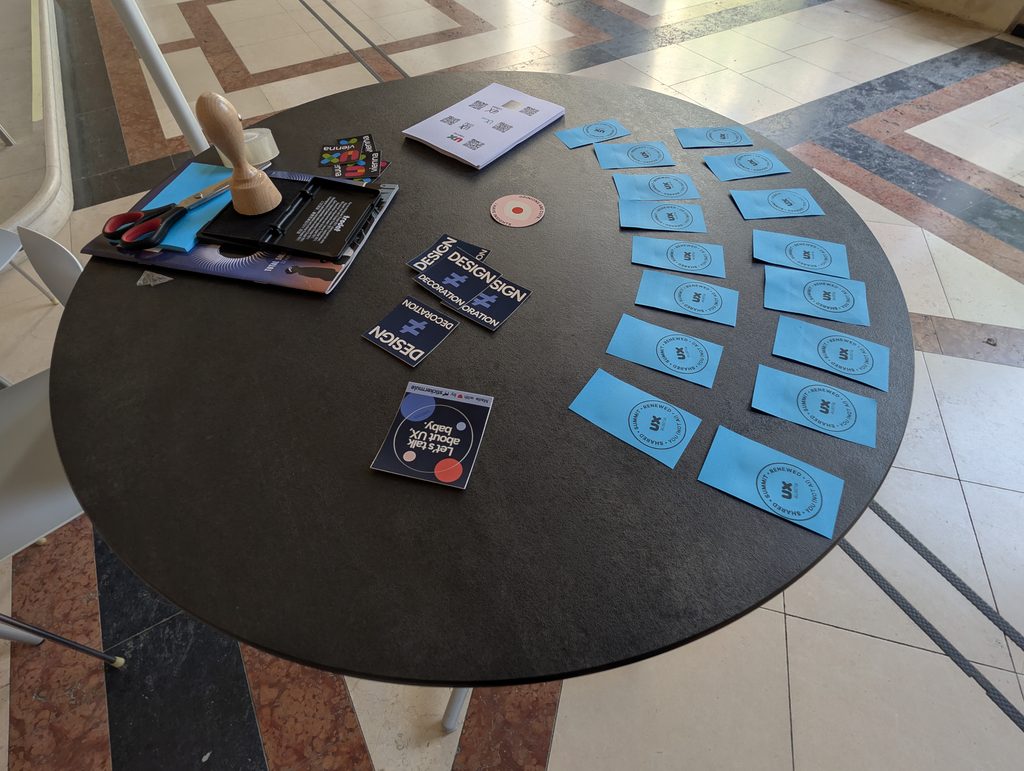 A round black table seen from above with a wooden stamp, small booklets and rows of blue notes arranged in an arc.